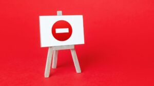 Computer illustration. Left of center wooden easel holding white horizontal canvas white centered red and white no entry sign on red background