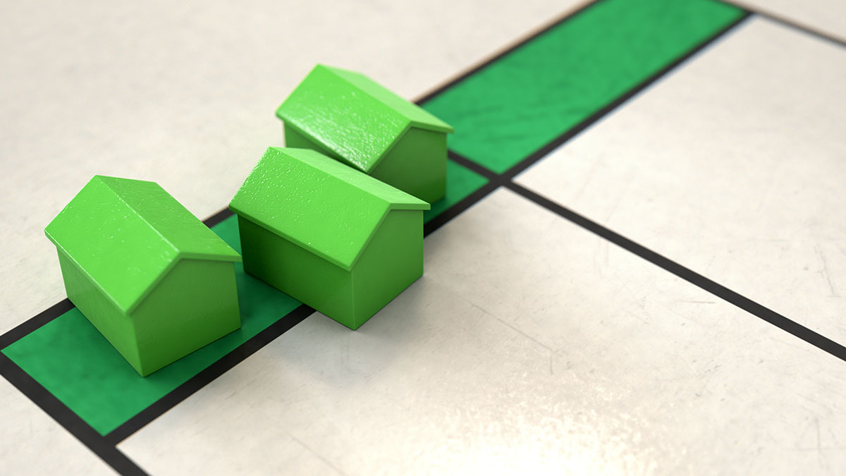 Casas verdes de madera en un tablero de juego de Monopoly