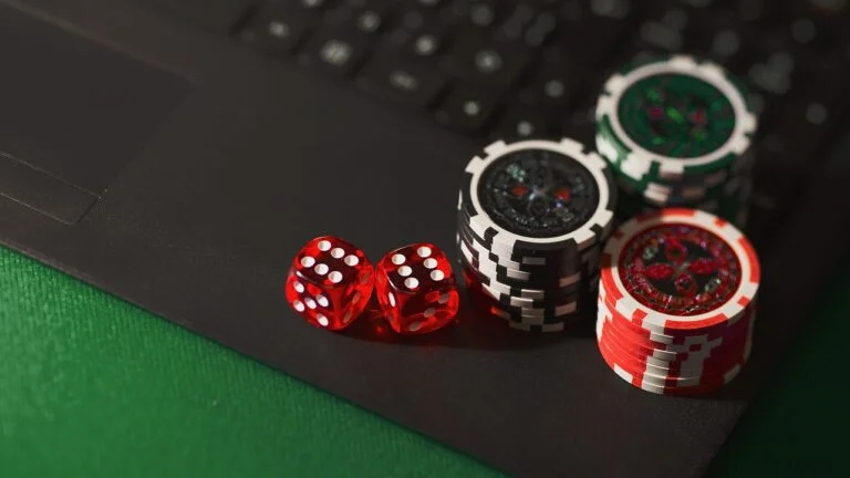 Stacks of casino chips and dice on a laptop