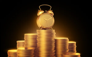 A gold alarm clock atop golden stacks of coins on a table