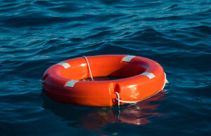 A red life preserver ring with white stripes floating on a water