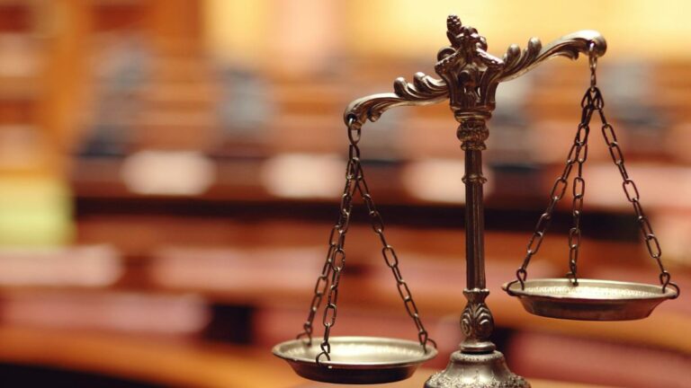 Appeal court upholds AGLC authority over Alberta online gambling site. Image: bronze legal scales, blurry courtroom background