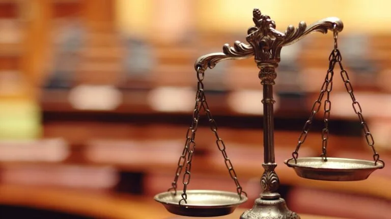 Appeal court upholds AGLC authority over Alberta online gambling site. Image: bronze legal scales, blurry courtroom background