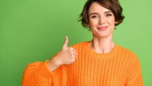 New Jersey regulator approves Kindred's in-house tech platform. Woman in orange gives thumbs up on green background