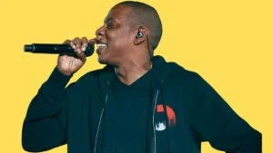 Roc Nation publishes open letter urging public support times square casino. Image Jay-Z wearing black performs in 2014. Yellow background