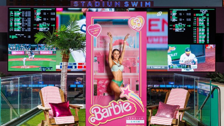 circa barbie activation raises responsible gambling questions. image woman in bikini poses in barbie box at circa resort & casino's stadium swim. background is giant screen showing live sports and betting lines