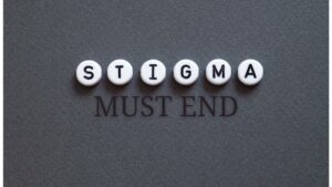 gambleaware research finds stigma creates barrier to problem gambling treatment. white beads black letters spell stigmas on gray background, black text reads must end