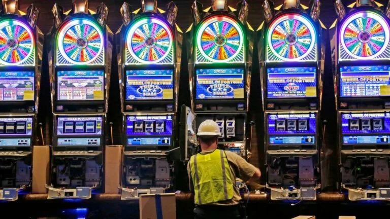muscogee creek nation sues poarch creek band and auburn university over alabama wind creek casino site. image show worker wriring machines at the casino in 2013