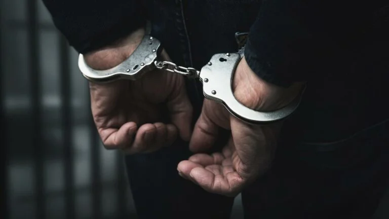 feds arrest man in decade-old illegal gambling indictment tiied to former congressman. close up of masculine hands behind back in handcuffs
