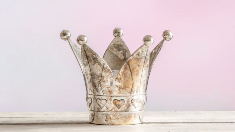 at betty gaming online casino rules. silver crown with hearts on a wooden table and pink background