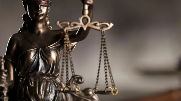 ex-staffer brown drops lawsuit against mgm springfield. broze statue of blind justice holds scale with blurred background