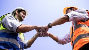 ground construction crew members bump fists