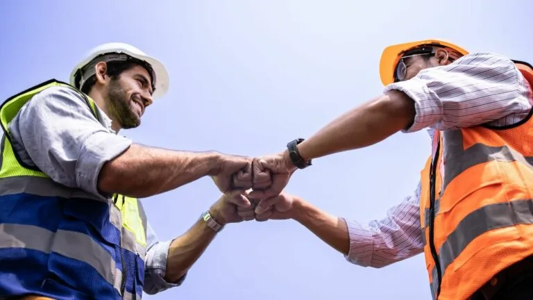 ground construction crew members bump fists