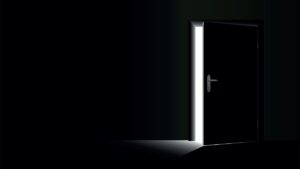 Dark room with light streaming in through the exit door, open only a crack