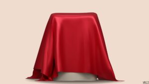 Beige background. A podium is centered in the forefront with a red, silky cloth draped over it, pre-reveal