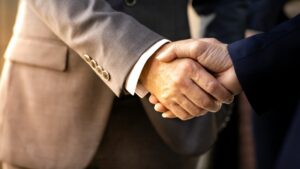 Close up of business handshake. Male coded arms wearing one gray and one navy business suit each shake hands