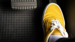 Close up of a person's foot in a simple yellow sneaker pushing accelerator pedal