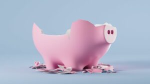 broken pink piggy bank against pale grey blue background. HIdden costs concept
