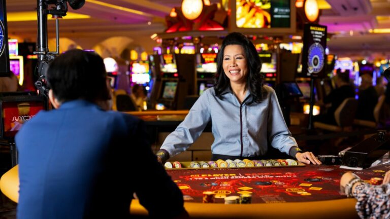 Smiling asian female live dealer enagining  players at Borgata Casino's Evolution-pod Dual Play Baccarat table