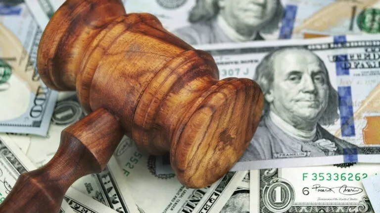 Close up of a wooden judge's gavel laying on its side on a pile of American bills of various denominations