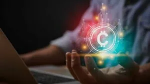 a digital cryptocurrency image over the hand of a man using a laptop computer