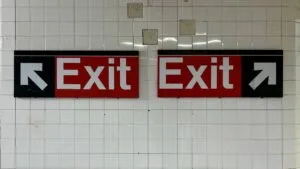 a pair of exit signs hanging in a new york subway station