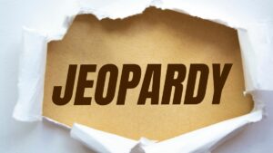 the word jeopardy appearing through a torn white background