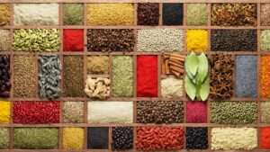 Overhead photo of large wooden spice tray divided into rectangle and squares sections filled with a colorful patchwork of spices