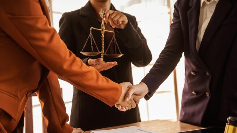 a group of lawyers shaking hands in front of a judge holding the scales of law