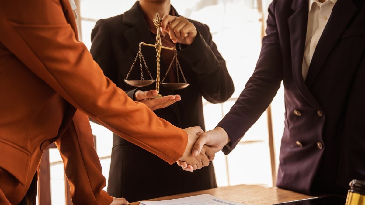 a group of lawyers shaking hands in front of a judge holding the scales of law