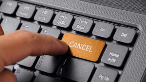 a finger hitting a key on a keyboard that reads cancel
