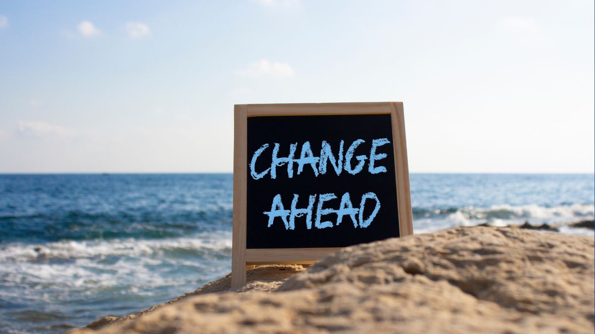 a chalkboard sign on a beach that says change ahead