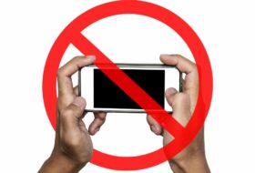 a person holding a cell phone with a banned symbol over it