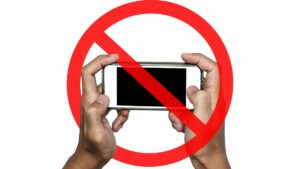 a person holding a cell phone with a banned symbol over it