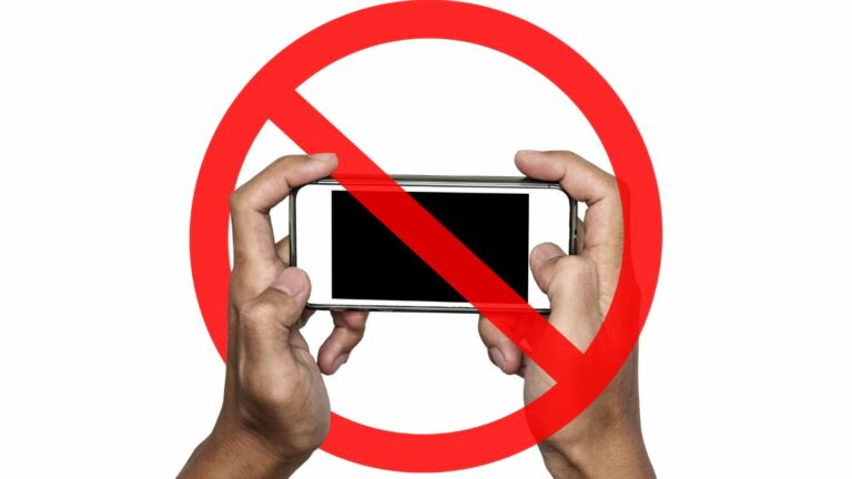 a person holding a cell phone with a banned symbol over it