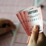 A young woman holds the lottery ticket with complete row of numbers