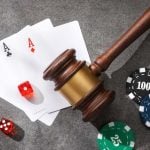 Judge gavel, poker chips, playing cards and dice on a gray stone surface