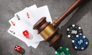Judge gavel, poker chips, playing cards and dice on a gray stone surface
