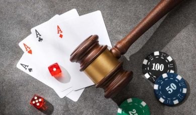 Judge gavel, poker chips, playing cards and dice on a gray stone surface