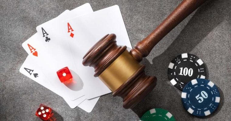 Judge gavel, poker chips, playing cards and dice on a gray stone surface