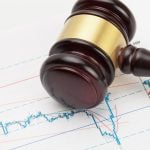Judge's gavel and calculator over stock market chart