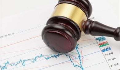 Judge's gavel and calculator over stock market chart