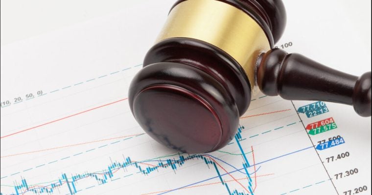 Judge's gavel and calculator over stock market chart