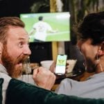 Two men watching football match and making bets