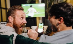Two men watching football match and making bets