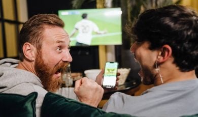 Two men watching football match and making bets
