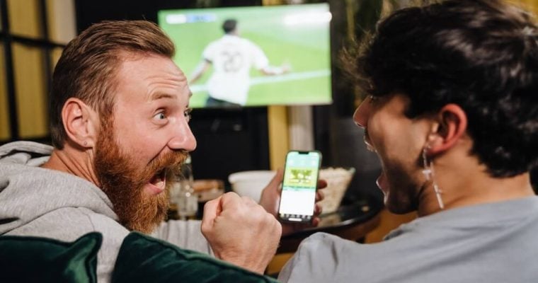 Two men watching football match and making bets