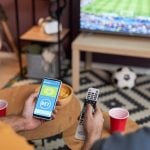 Two men watching football match and placing online sports bets