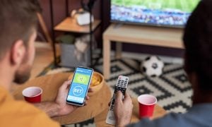 Two men watching football match and placing online sports bets