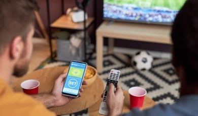 Two men watching football match and placing online sports bets